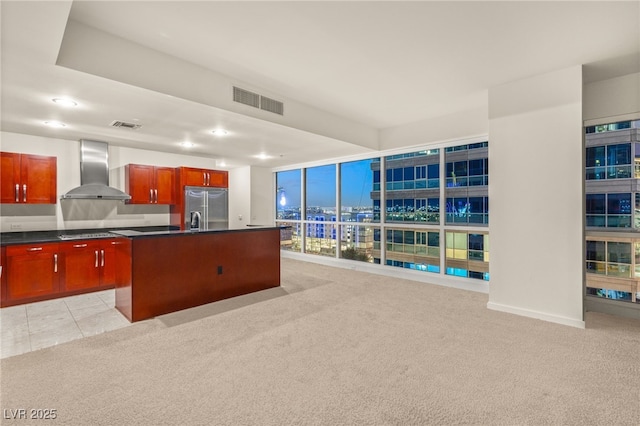 kitchen featuring wall chimney range hood, light carpet, visible vents, and stainless steel built in fridge