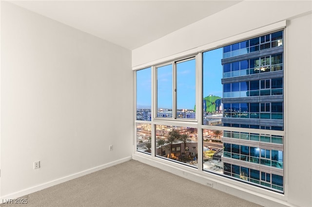 carpeted spare room with a healthy amount of sunlight, a view of city, and baseboards