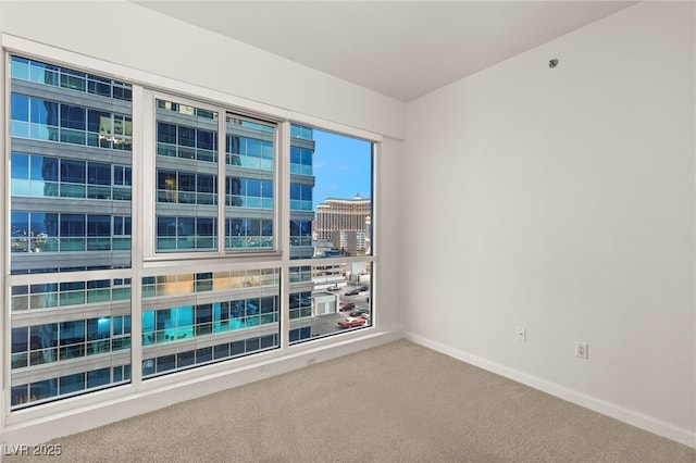 spare room featuring a view of city, baseboards, and carpet floors