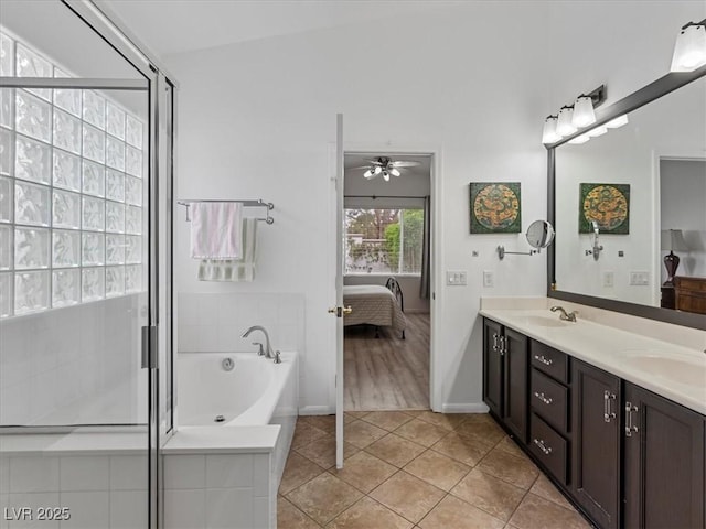 ensuite bathroom with a ceiling fan, a sink, tile patterned floors, a bath, and connected bathroom