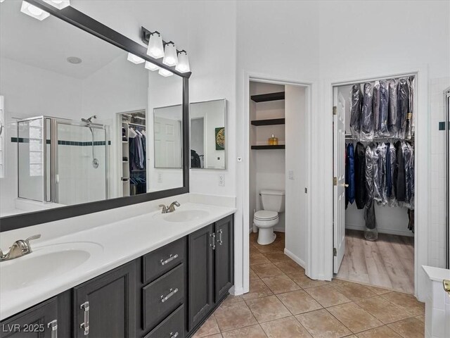 full bath featuring tile patterned flooring, a stall shower, toilet, and a sink