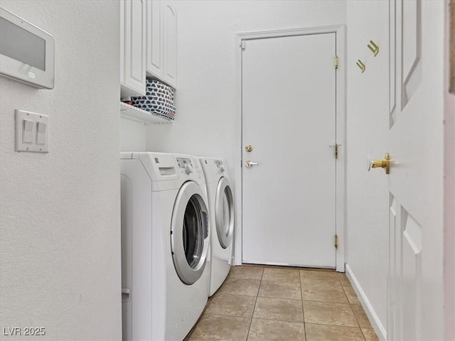 washroom featuring washing machine and clothes dryer, light tile patterned floors, cabinet space, and baseboards