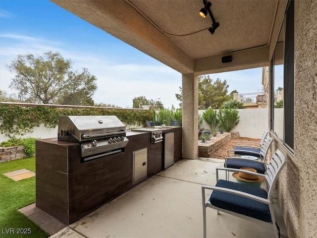 view of patio featuring exterior kitchen, a fenced backyard, and grilling area