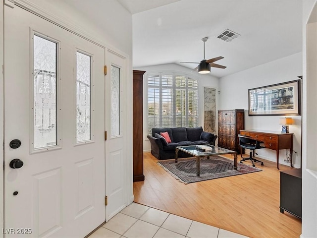 foyer entrance featuring light tile patterned floors, visible vents, ceiling fan, and vaulted ceiling