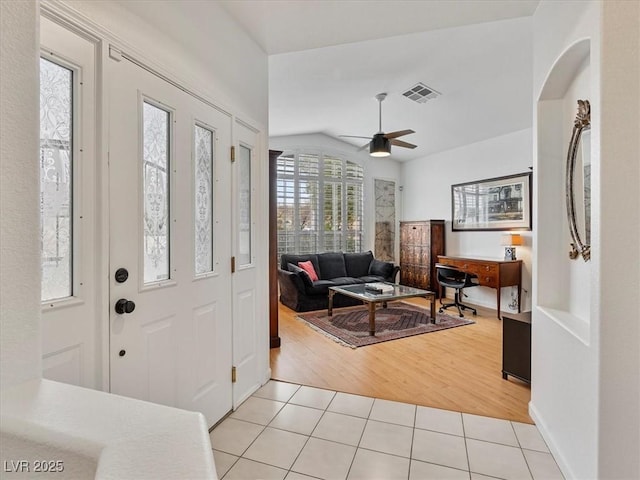 foyer entrance featuring light tile patterned floors, visible vents, lofted ceiling, and ceiling fan