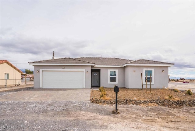 ranch-style home with a garage, fence, driveway, and stucco siding