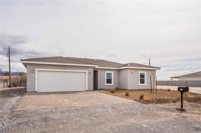 view of front of house with stucco siding, an attached garage, and decorative driveway