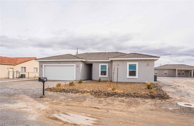 single story home with stucco siding, driveway, fence, a garage, and central AC unit