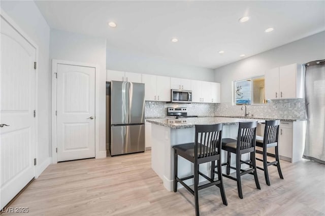 kitchen with a sink, stainless steel appliances, a kitchen island, and white cabinetry