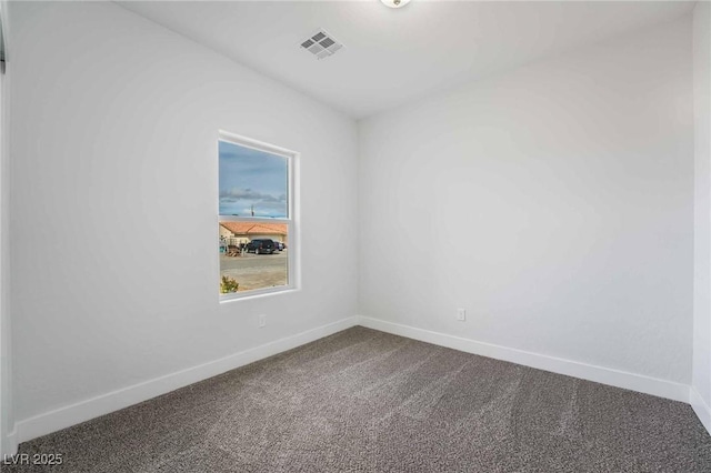 unfurnished room featuring baseboards, visible vents, and dark carpet