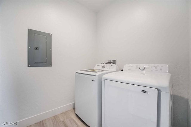 clothes washing area featuring baseboards, light wood-type flooring, electric panel, laundry area, and washer and dryer