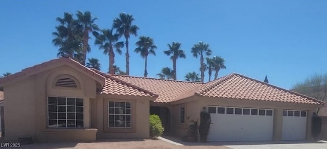 mediterranean / spanish-style house with stucco siding, concrete driveway, an attached garage, and a tiled roof