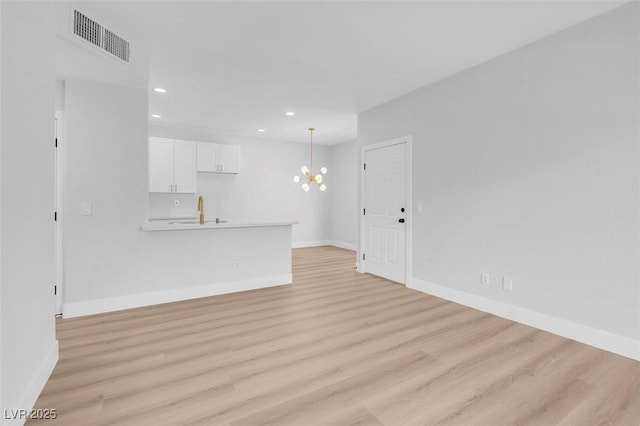 unfurnished living room with baseboards, visible vents, recessed lighting, a notable chandelier, and light wood-type flooring