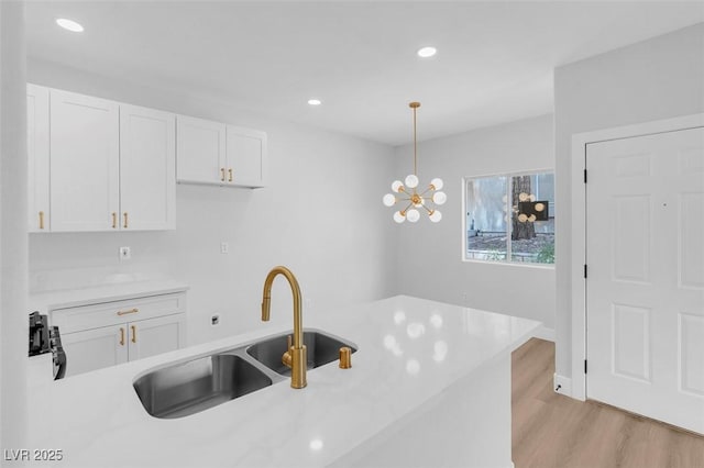 kitchen featuring light countertops, white cabinets, light wood-type flooring, and a sink