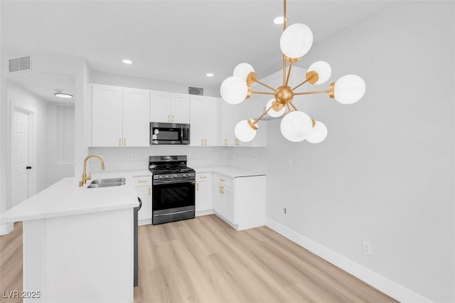 kitchen with visible vents, light countertops, a peninsula, stainless steel appliances, and a sink