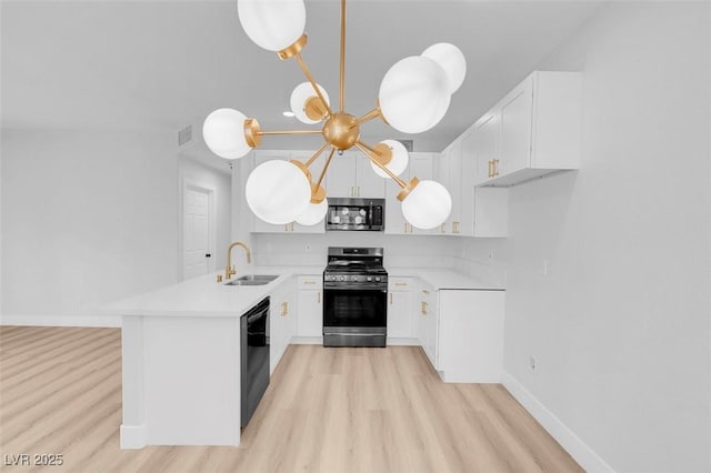 kitchen featuring a peninsula, a sink, light countertops, appliances with stainless steel finishes, and light wood-type flooring