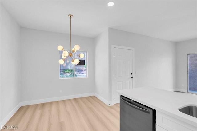 kitchen with dishwasher, light countertops, baseboards, and white cabinetry