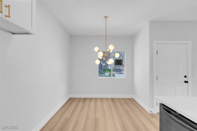 unfurnished dining area featuring a chandelier, light wood finished floors, and baseboards