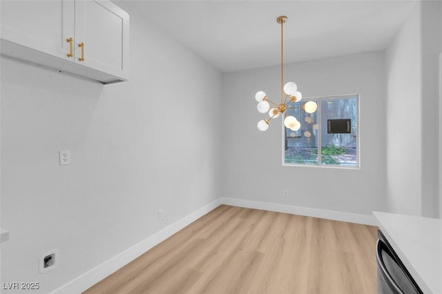 unfurnished dining area featuring an inviting chandelier, light wood-style floors, and baseboards