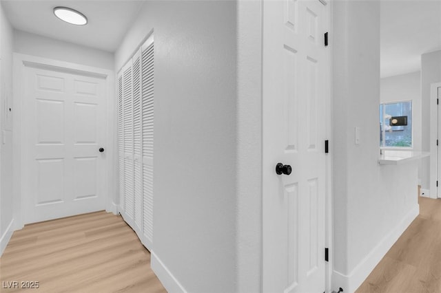 corridor featuring light wood finished floors and baseboards