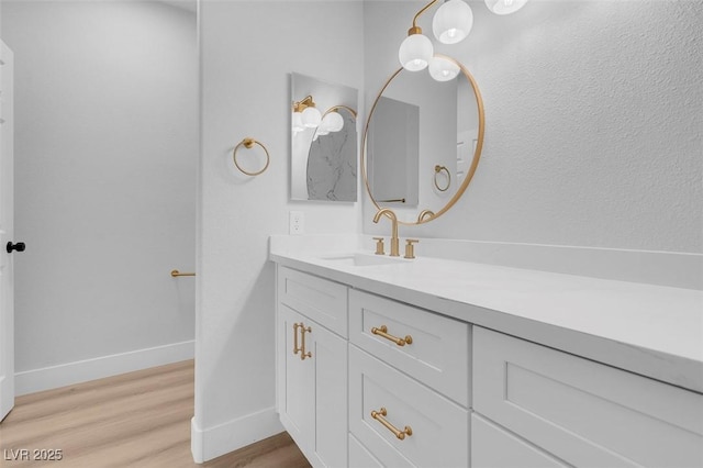 bathroom with vanity, wood finished floors, and baseboards