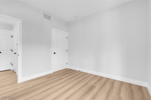 spare room featuring light wood-style flooring, baseboards, and visible vents