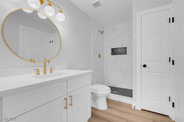 full bath with a marble finish shower, visible vents, toilet, wood finished floors, and vanity