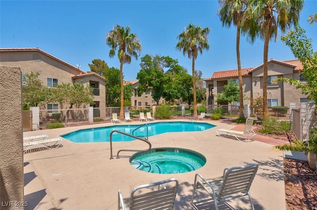 community pool featuring a patio, fence, a residential view, and a hot tub