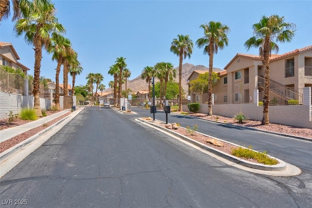 view of road featuring a gated entry, a residential view, curbs, and a gate