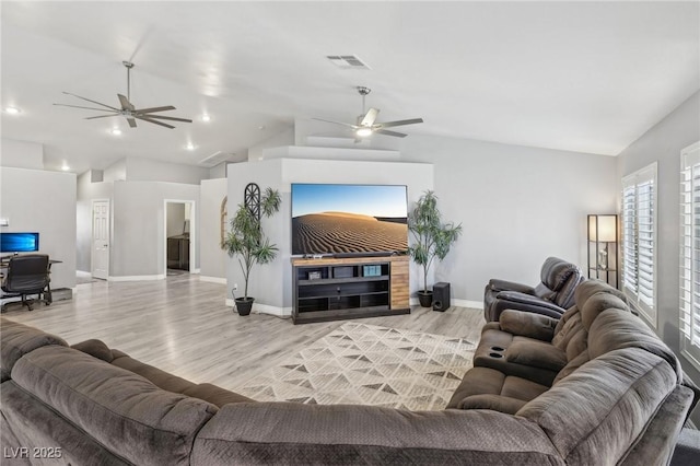 living area with a ceiling fan, wood finished floors, a fireplace, baseboards, and vaulted ceiling