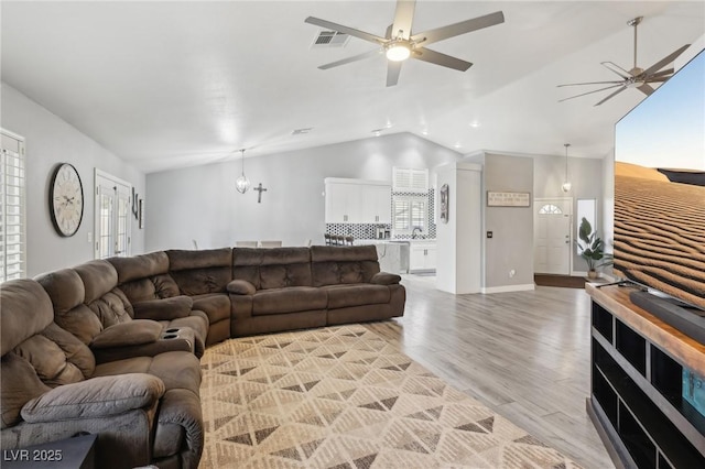 living room with visible vents, ceiling fan with notable chandelier, light wood-type flooring, and lofted ceiling