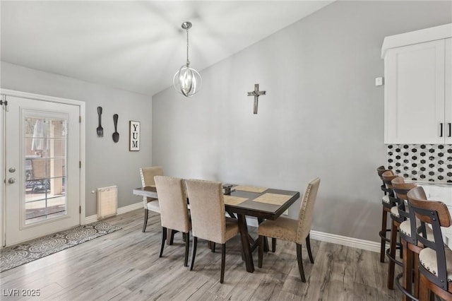 dining room featuring baseboards, lofted ceiling, a notable chandelier, and light wood-style flooring