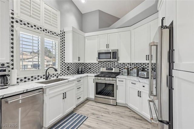 kitchen with a sink, white cabinets, tasteful backsplash, and stainless steel appliances