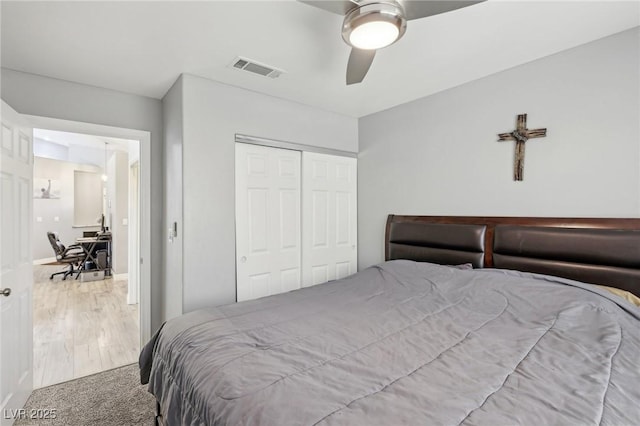 bedroom featuring visible vents, carpet, wood finished floors, a closet, and a ceiling fan