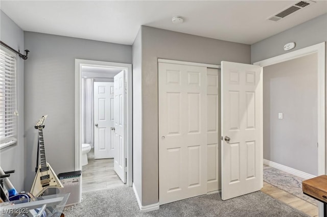 unfurnished bedroom featuring baseboards, visible vents, carpet floors, ensuite bath, and a closet