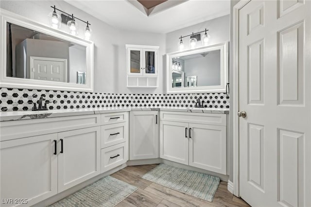 bathroom featuring double vanity, wood finished floors, tasteful backsplash, and a sink