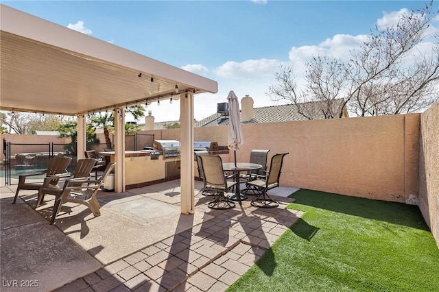 view of patio featuring a fenced backyard, an outdoor kitchen, outdoor dining space, and grilling area