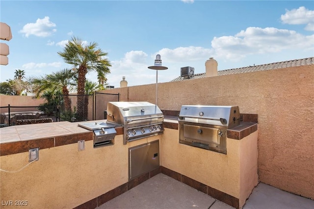 view of patio / terrace featuring grilling area, exterior kitchen, and fence