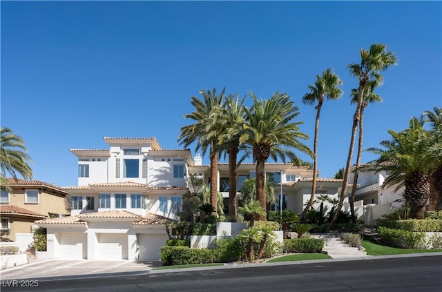 mediterranean / spanish house featuring a tile roof, concrete driveway, a garage, and stucco siding