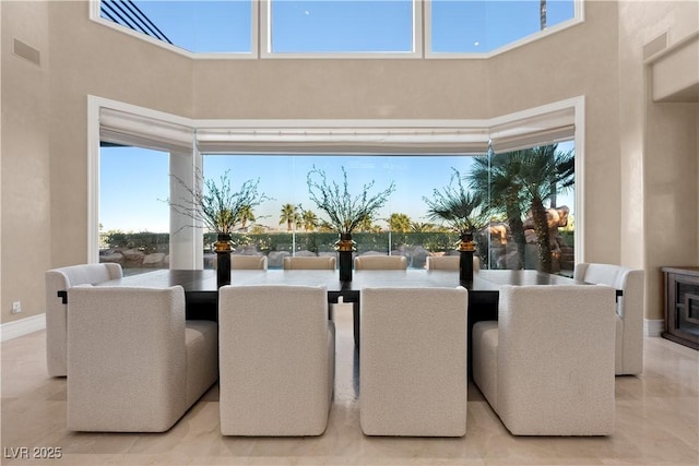 dining space featuring visible vents, baseboards, and a towering ceiling