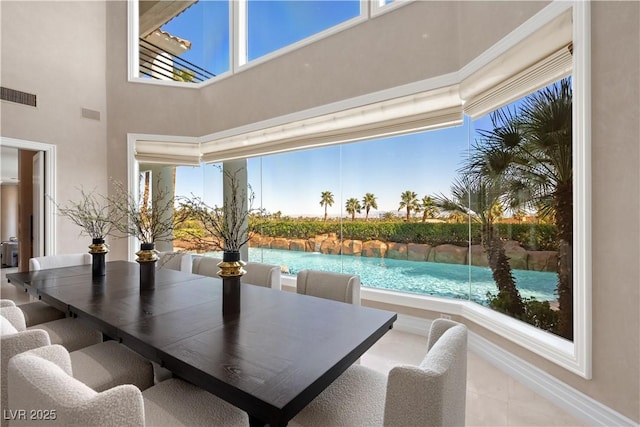 dining area with a wealth of natural light, visible vents, baseboards, and a towering ceiling