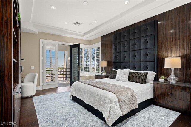 bedroom featuring dark wood finished floors, access to exterior, visible vents, and a raised ceiling