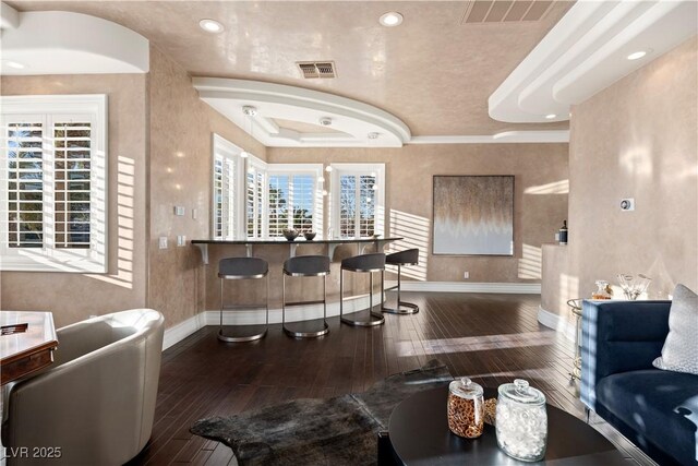 interior space with visible vents, a tray ceiling, baseboards, and hardwood / wood-style flooring