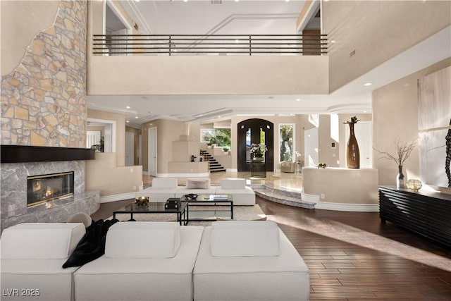 living area with stairway, wood finished floors, a high ceiling, and a high end fireplace