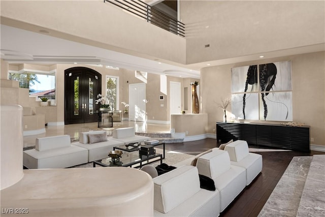 living area featuring recessed lighting, wood finished floors, baseboards, and a towering ceiling