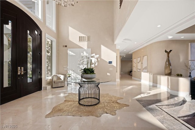 foyer entrance featuring an inviting chandelier, french doors, visible vents, and marble finish floor