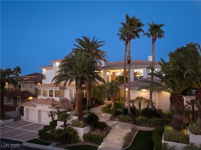 mediterranean / spanish home with stucco siding, concrete driveway, a tile roof, and a garage