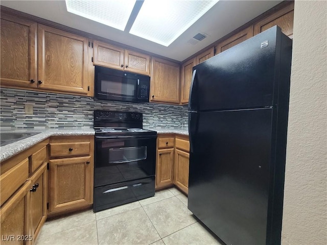 kitchen featuring tasteful backsplash, brown cabinetry, light countertops, light tile patterned flooring, and black appliances