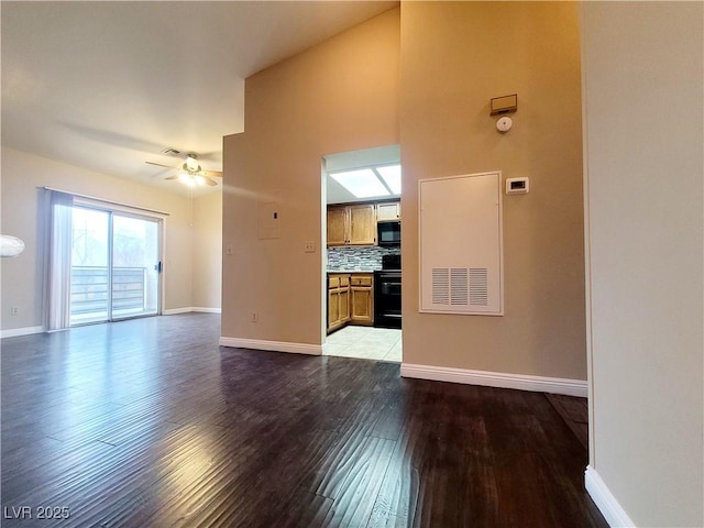 unfurnished living room with a ceiling fan, visible vents, wood finished floors, and baseboards