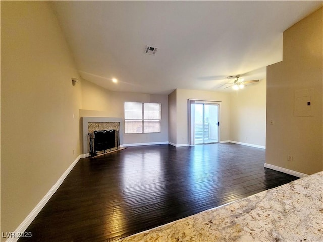 unfurnished living room featuring visible vents, baseboards, a fireplace, dark wood-style floors, and a ceiling fan